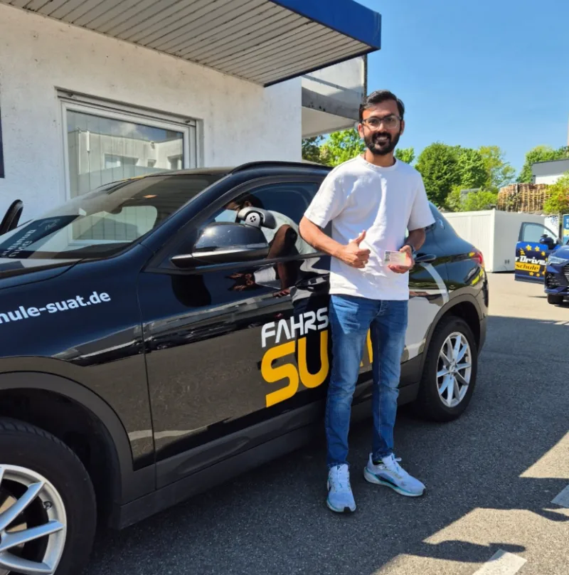 Fahrschüler der Fahrschule Suat mit seinem neuen Führerschein vor dem Fahrschulauto